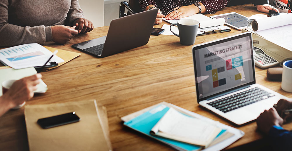 A group of people sat around a table, each with different digital services on their screens