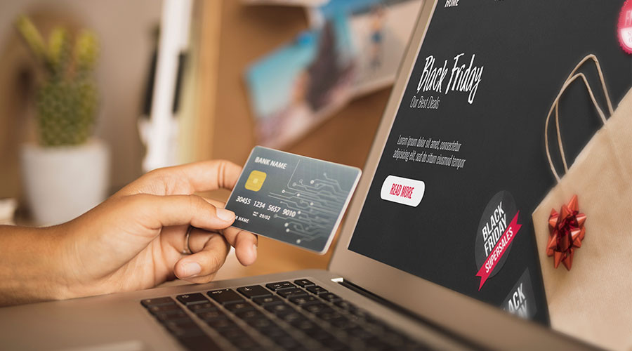 Someone holding a bank card in front of their laptop screen which is on an e-commerce website