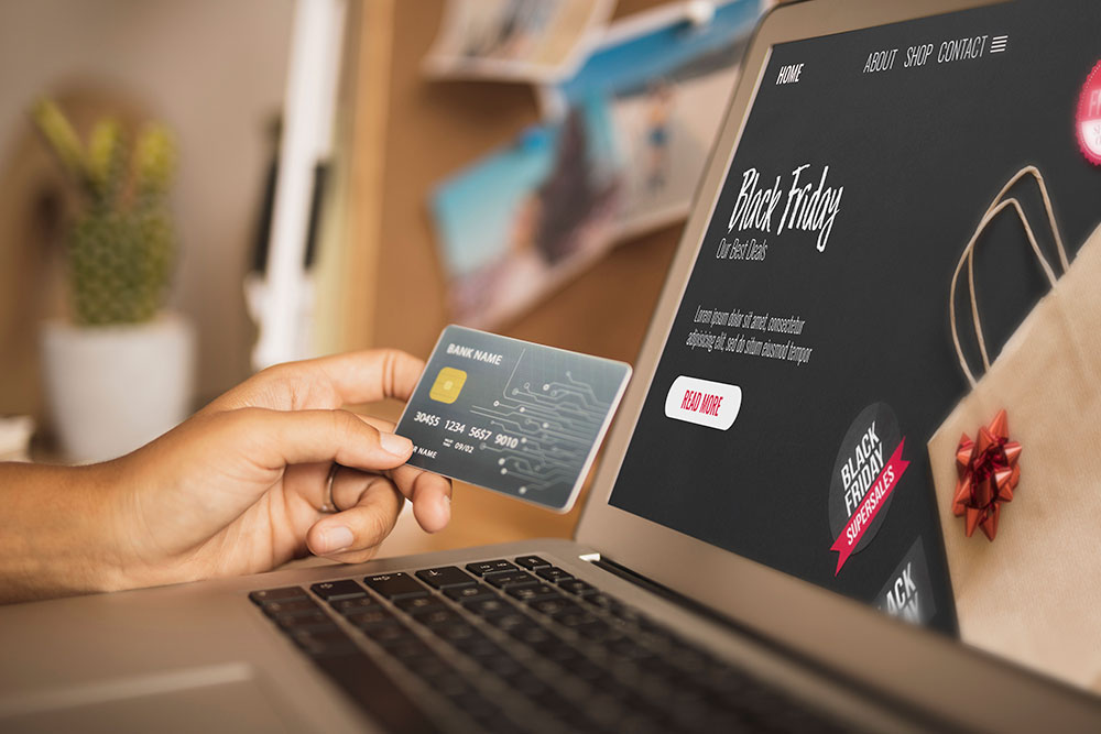 Someone holding a bank card in front of their laptop screen which is on an e-commerce website