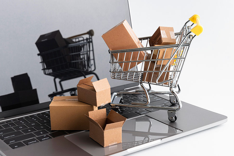 A small shopping trolley on to of a laptop to signify online shopping