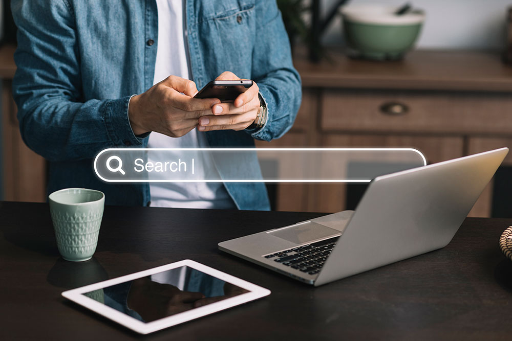 A man with multiple devices and a search engine bar hovering in the middle