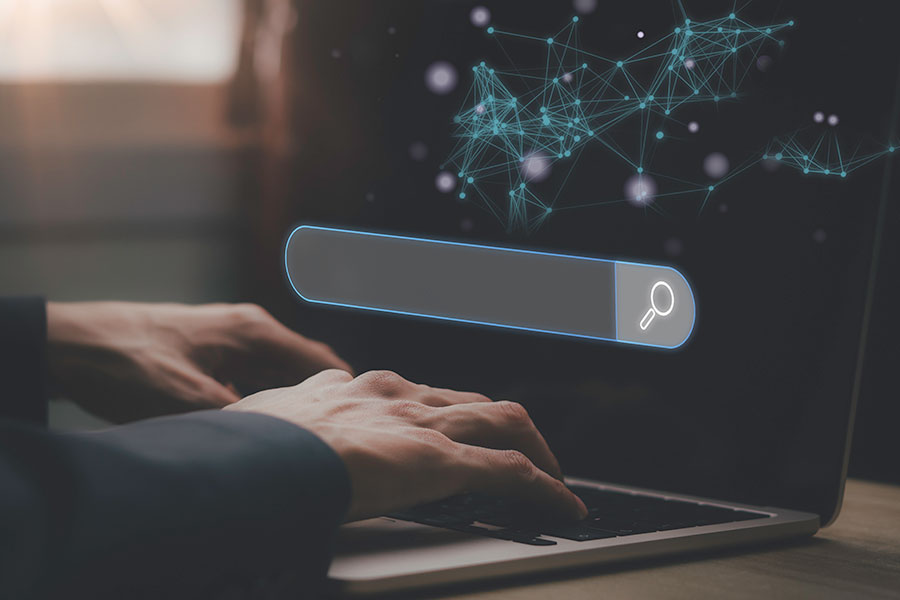 A person sat at a laptop with a search bar hovering over the keyboard, representing SEO services