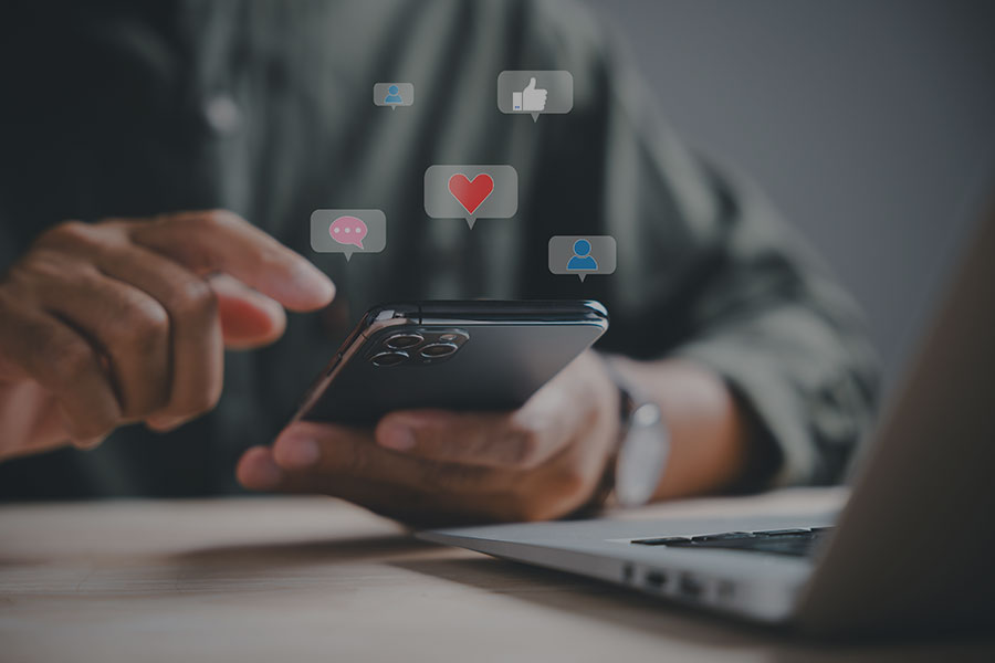 A person holding a mobile phone which various social media icons above it