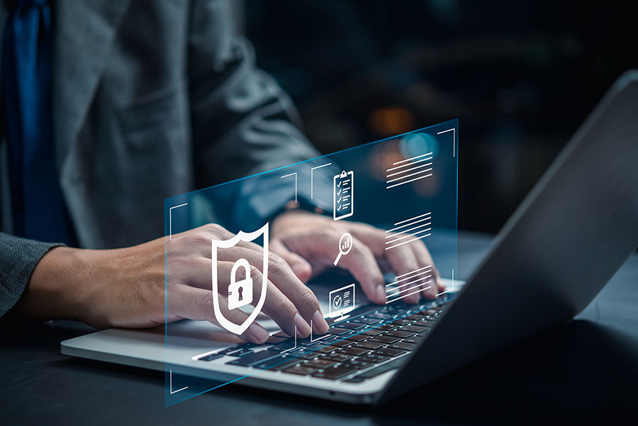A person sat at a laptop with security and maintenance icons hovering over the keyboard