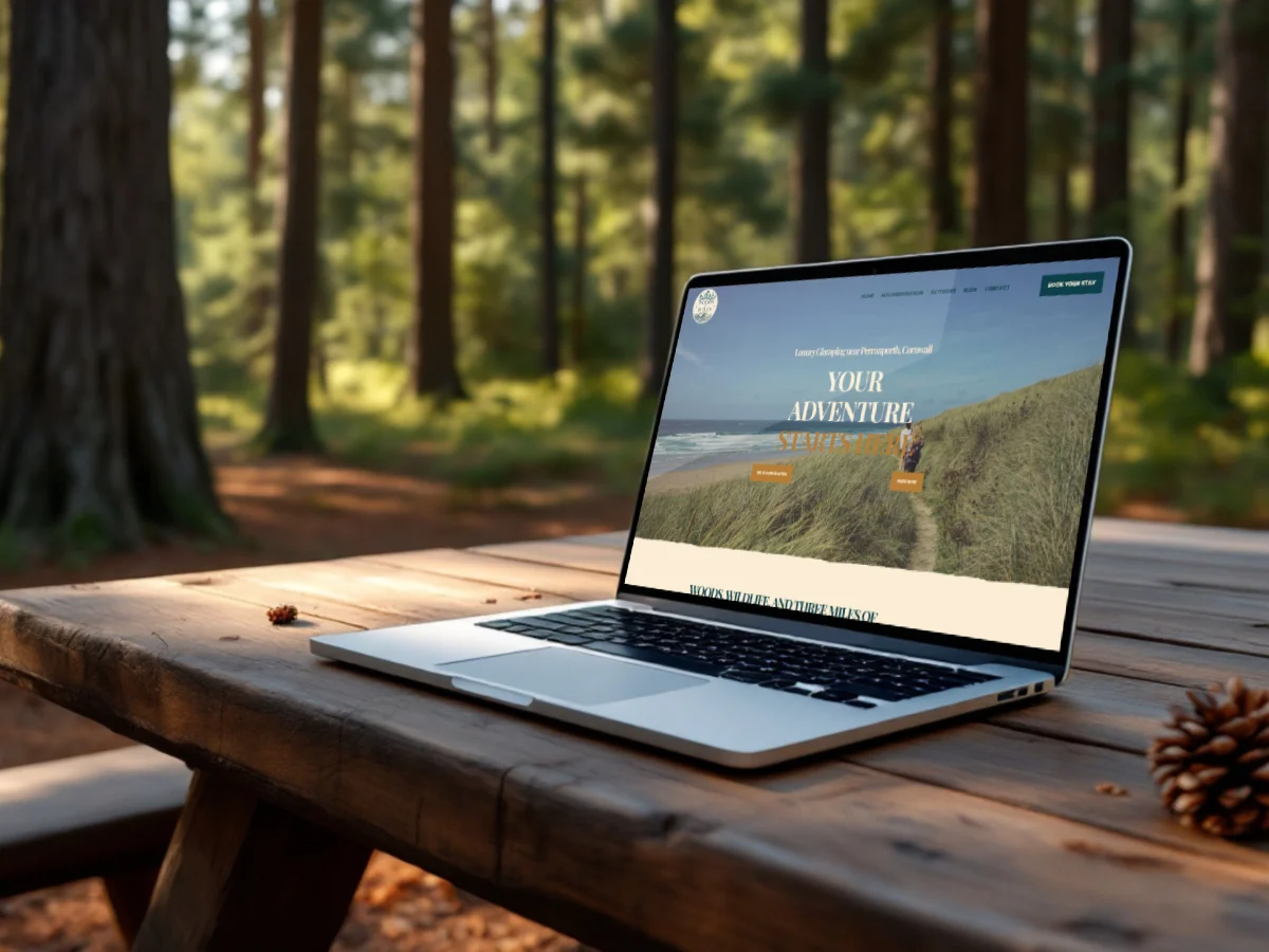 Woods 2 Waves homepage shown on a laptop on a wooden table in Cornish woodland